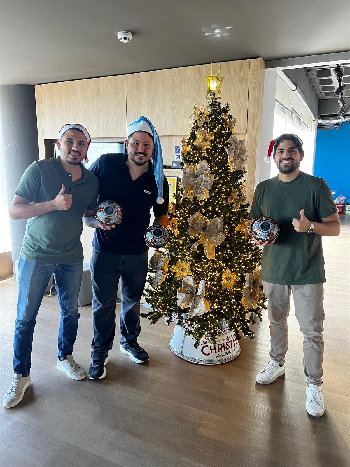 Colaboradores da Praso ao lado de árvore de Natal no escritório